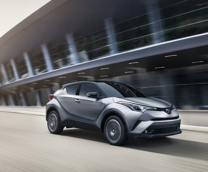 Side-angled shot of the 2019 C-HR limited in silver knockout metallic driving at speed in an urban area.