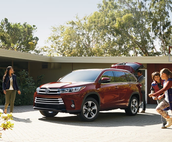 Front-angled shot of the 2019 Highlander limited in Ooh La La Rouge Mica parked in front of a family home.