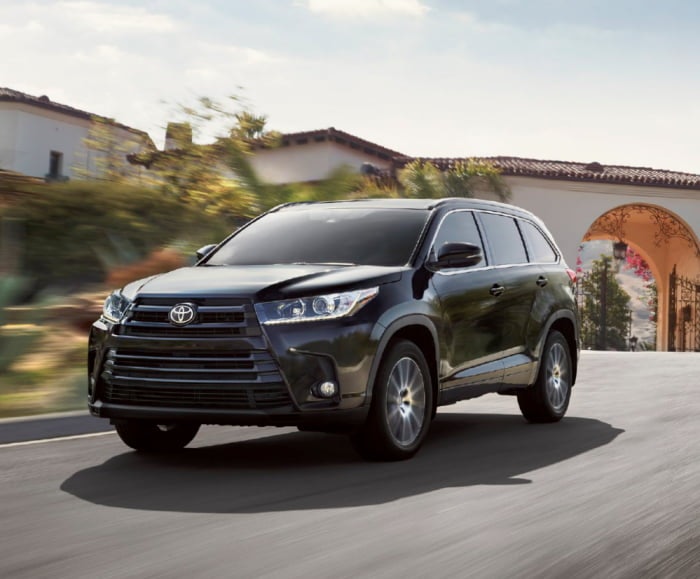 Front-angled shot of the 2017 Highlander SE in Midnight Black driving in a residential area.