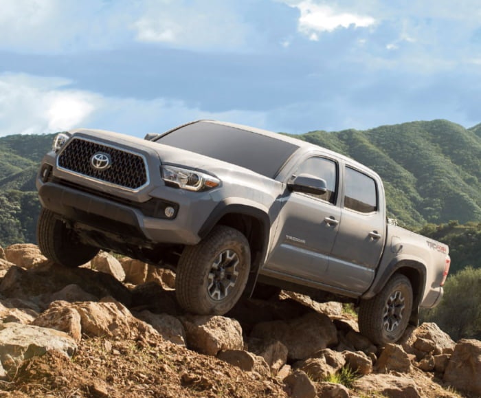 Side-angled view of the Toyota Tacoma TRD Off-Road Double Cab shown in Cement traversing over a ridgeline.