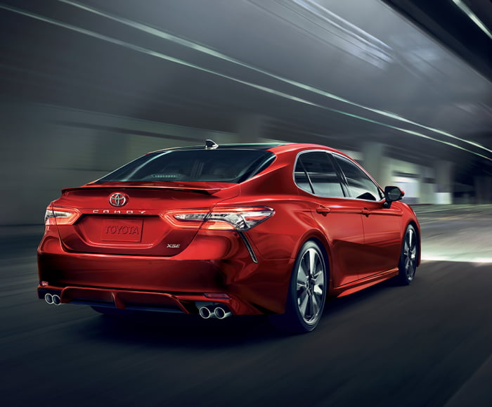 7/8 rear passenger view of 2019 Camry in Supersonic Red driving through tunnel.