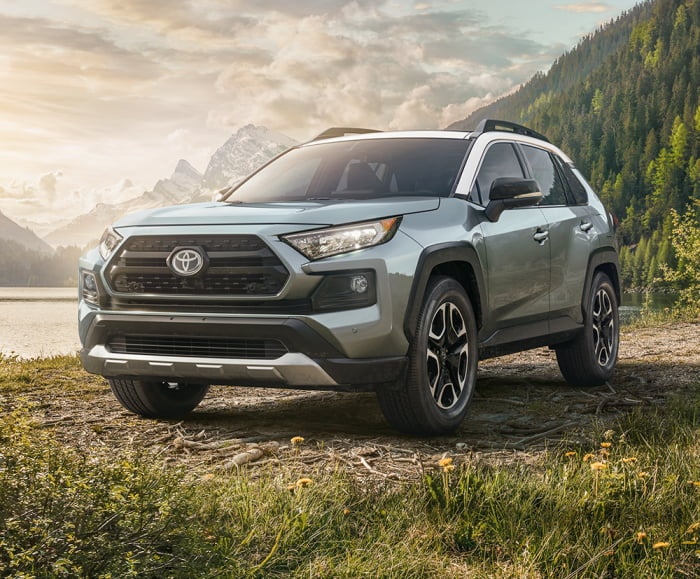 2019 RAV4 in Lunar Rock parked by mountain in front of lake.