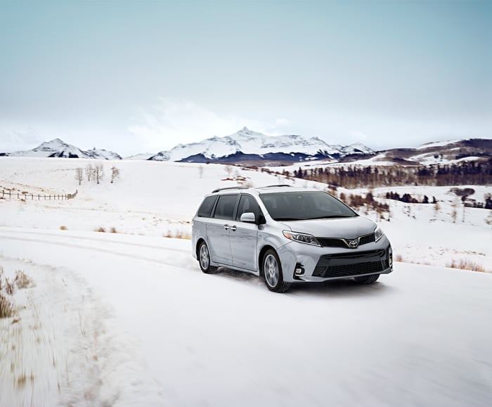 Performance shot of Toyota Sienna in Super White driving on a snowy road.