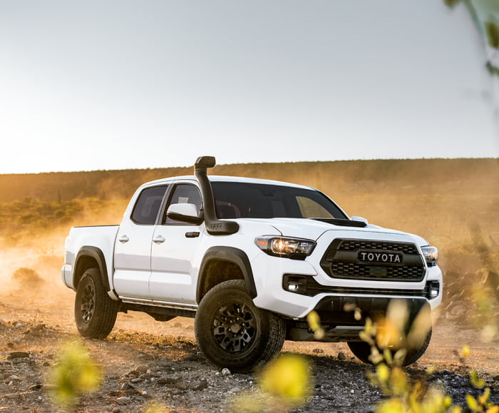 Side-angled shot of the Toyota Tacoma TRD Pro in Super White driving on a desert off-road. 