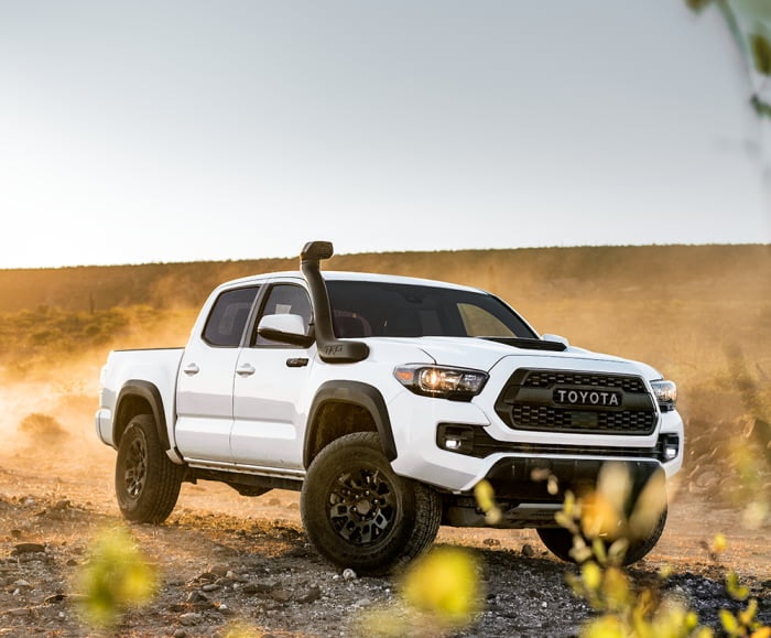 Side-angled shot of the Toyota Tacoma TRD Pro in Super White driving on a desert off-road.