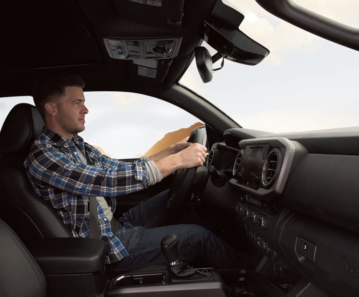 Interior side-shot of the Toyota Tacoma TRD Pro in black with man in driver's seat.