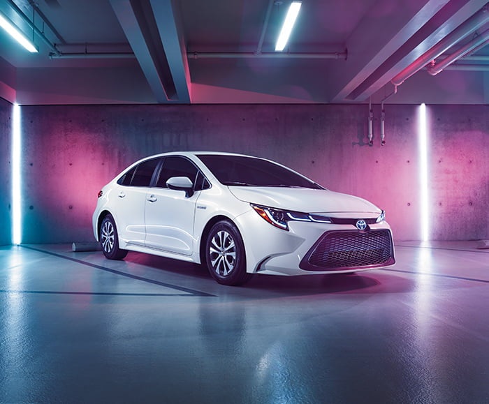 Exterior passenger side view of 2020 Corolla Hybrid LE in underground parking garage in Blizzard Pearl.