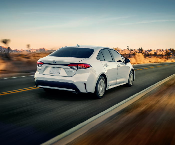 Rear passenger view of 2020 Corolla LE in Blizzard Pearl on highway.